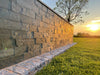 An image of a wall with Riverstone Natural Slate Cladding stone with a sunset in the background