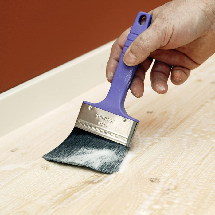 An image of Sikagard Universal 5 Star Wood Treatment being applied to a wooden surface with a brush