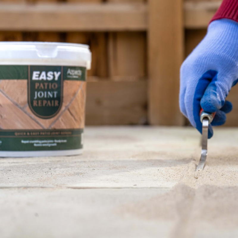 An image showing Azpects EASY Patio Joint Repair in the colour Grey Beige being pressed into gaps in paving ready to use