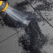 An image of a 12.5kg tub of EasyJoint Select Paving Compound being washed into cracks in paving.