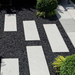 An image of black basalt aggregate stones on a garden with contrasting white slabs to show the finish it gives.