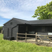 An image of a Black agricultural building with a wooden cladding and Pantile 2000 roofing tiles with Barge End Caps.