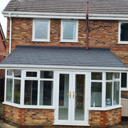 An image of a lean to conservatory with Britmet lightweight tiles and finished with Apron Roof Flashing strips.