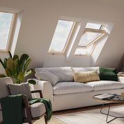 An image showing a Dakea Ultima Comfort Centre Pivot Roof Window with a wooden frame in a living room