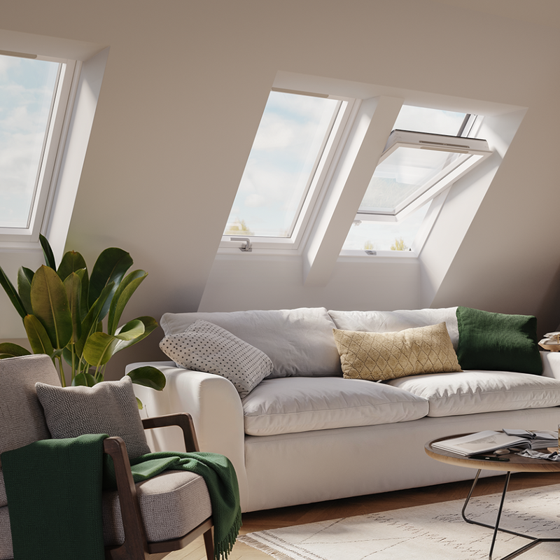 An image showing a Dakea Ultima Comfort Centre Pivot Roof Window with a white frame in a living room