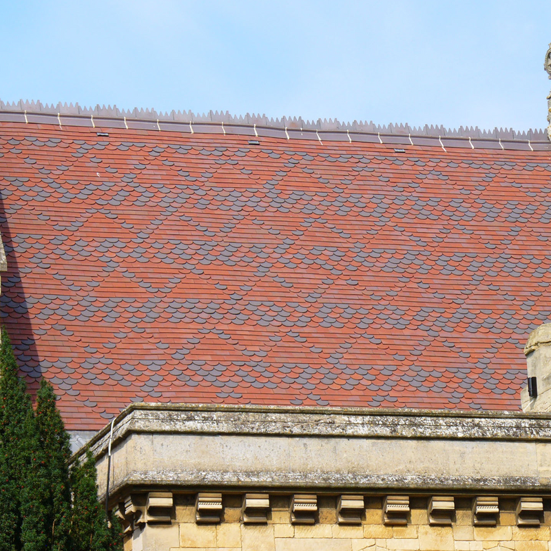An image showing a roof of Dreadnought Clay Tiles with Bullnose details, they are Smooth Red / Blue Blend in colour
