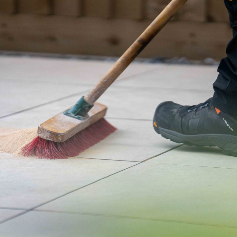 Image of Azpects EasyJoint Porcelain Next-Gen Jointing Paving Compound being swept into joins in paving using a normal outdoors yard brush.