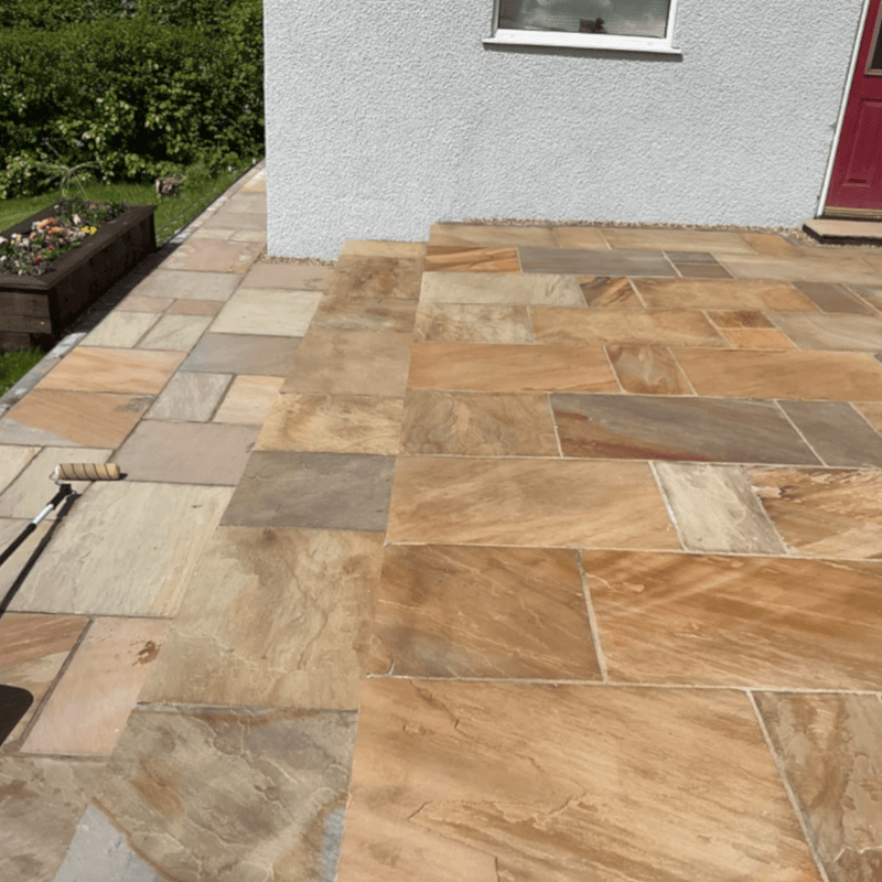 An image of EasySeal Sandstone Sealer & Enhancer that has been applied to half of a patio to show the difference. It makes the stone colour  deeper and shows off the tones in the colour tones on the slabs.