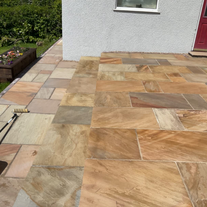 An image of EasySeal Sandstone Sealer & Enhancer that has been applied to half of a patio to show the difference. It makes the stone colour  deeper and shows off the tones in the colour tones on the slabs.