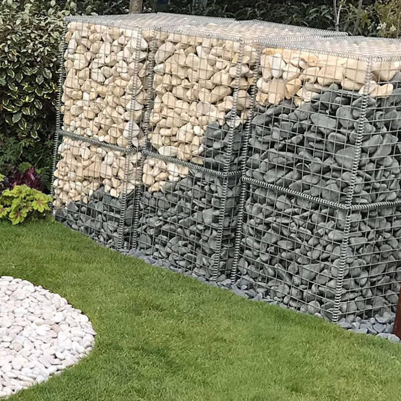An image showing Ebony Cobble Stone Aggregate Gravel. They are piled in cages as decoration in a garden.