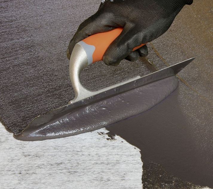 An image of Everbuild Black Jack 903 Trowel Mastic being spread onto a surface with a trowel.