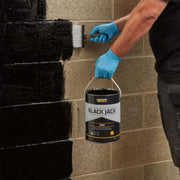 An image of Black Jack DPM 908 being applied to a brick wall with a brush.
