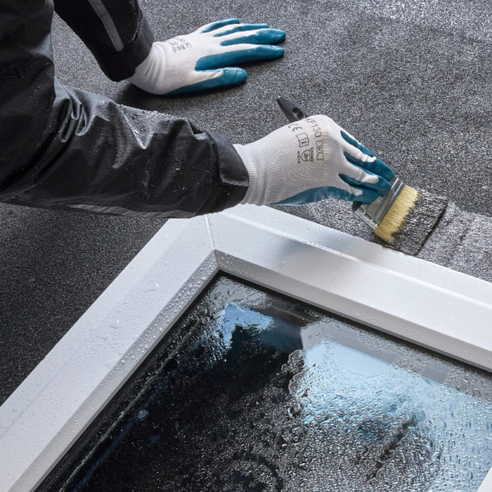 An image of Everbuild Evercryl One Coat Roof Repair being applied with a brush around a window frame in the wet to show it can be used when wet and raining to repair leaks around windows.