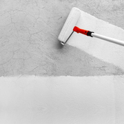 An image of Everbuild Filler Coat being applied to a wall that has cracked plaster with a roller.