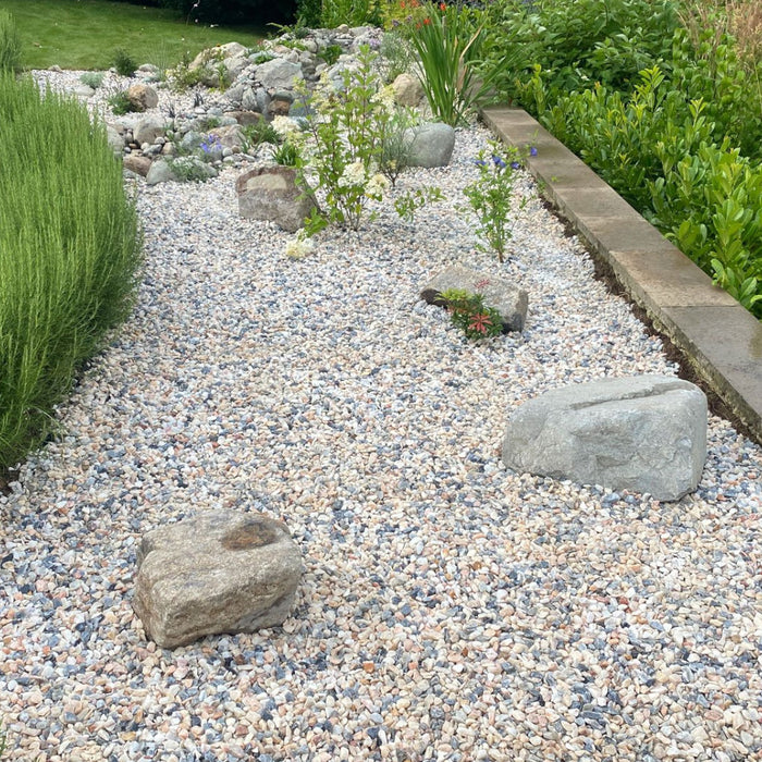 An image of Flamingo Chippings 20mm laid out on a flower bed to show the finish