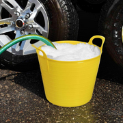 An image showing a Flexible Tub / Bucket. It is Yellow and have been used to hold water while washing a car.