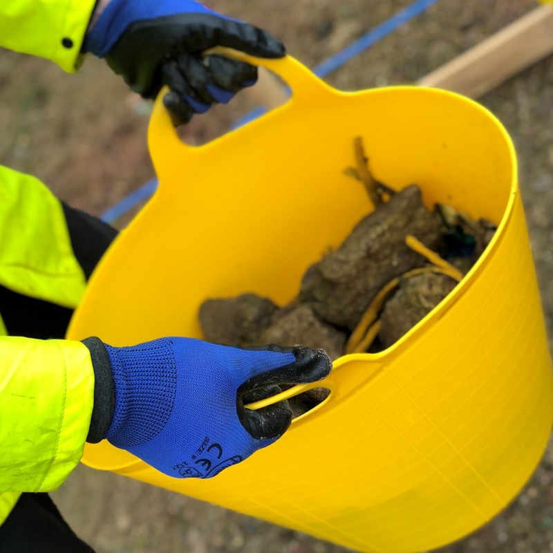 An image showing a Flexible Tub / Bucket. It is Yellow and have been used to carry rubble on a building / construction site.