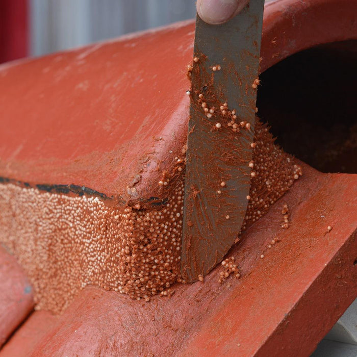 A close up image of Flexim Roof Putty being used around a ridge tile and being cut and shaped by a putty knife.