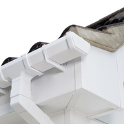 An image of a FreeFoam Magnum Leg Fascia Board in White mounted on a roof behind guttering.