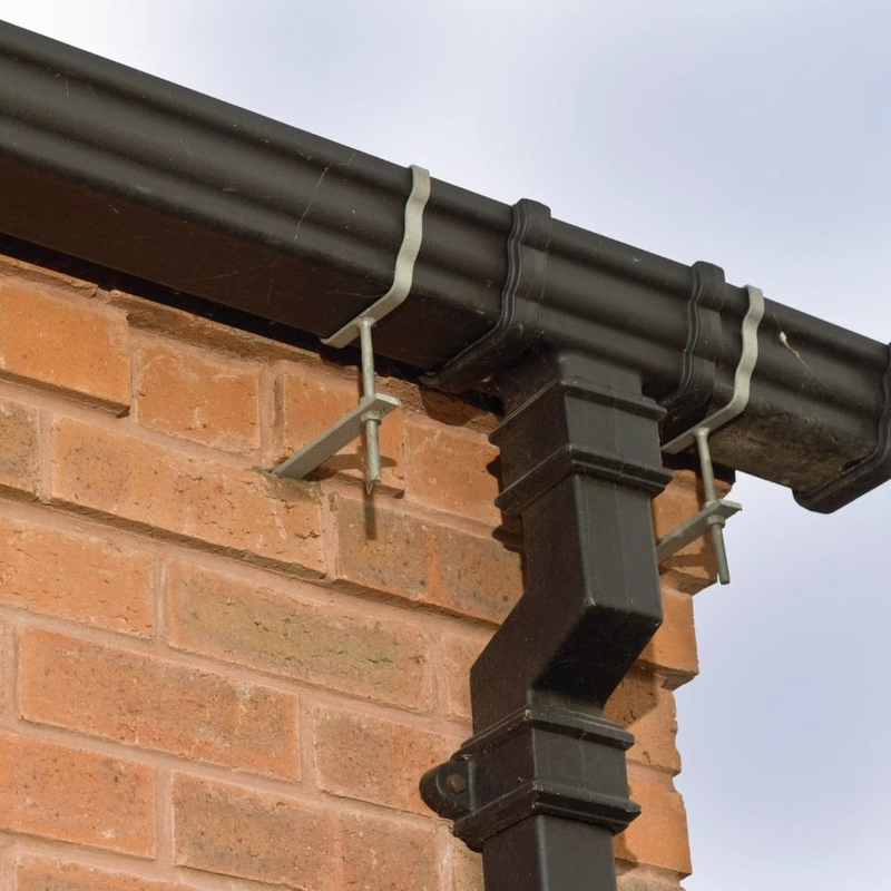 An image showing a Galvanised Rise and Fall Gutter Bracket Spike driven into the mortar on the side of a house, used with a rise and fall bracket to support an iron gutter.
