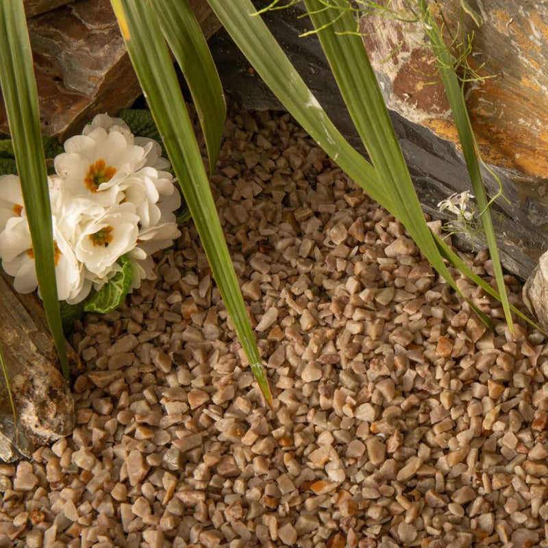 An image of Heritage Quartz gravel stones laid in a garden to show what they look like when wet,