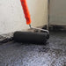 A image of IKO Self Adhesive Roofing Felt Bitumen Primer being applied to a surface with a roller.