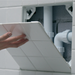 An image of a Manthorpe Tile Access Panel GLTAP-500 being used to cover pipes and covered with White tiles