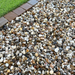 An image of aggregates in the colour Moonstone which are 20mm. They are laid on a patio next to some grass to give an idea of when they look like.