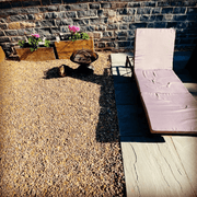 Image of aggregates in the colour Pink Champagne in 20mm. They are tan and pink shades. The image shows what it looks like laid out on a large patio