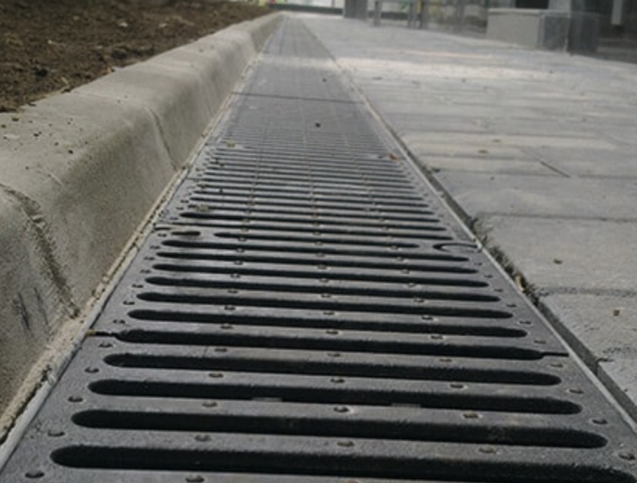 An image of the Plastic Lid/Grate Garage Drainage Kits. fitted along the side of a curb to help with water run-off.