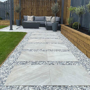 An image of Polar White garden Stones and what they look like when laid out on a garden path around paving slabs.