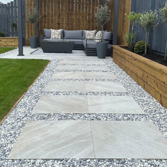 An image of Polar White garden Stones and what they look like when laid out on a garden path around paving slabs.