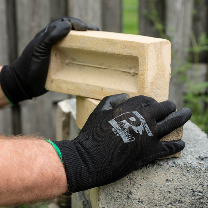 An image of Pred Jet Safety Gloves in the colour black. The person in the image is handling bricks to show they are robust for building projects