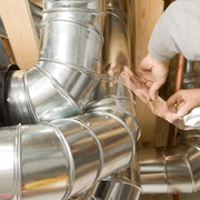 An image showing a person working with metal ductwork and using Prosolve Aluminium Foil Tape 75mm to join and seal them.