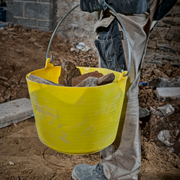 Image of a Red Gorilla Flexible Bucket in Yellow being used to carry rubble to show how robust it is.