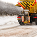 Image of rock salt being used by a spreading truck to de-ice a road.