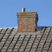 An image of the base of a chimney stack with Rose Roofing Self Adhesive Flashing Tape applied to seal the join between the tiles and brick.