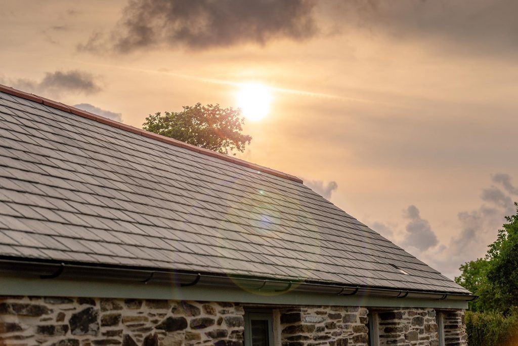 An image of SSQ Riverstone Ultra slate tiles on a roof to show the finish against a sunset