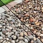 An image of a patio with Scottish Pebbles, 20-40mm-20kg. The image is diagonally cut to show what they look like when wet and dry.