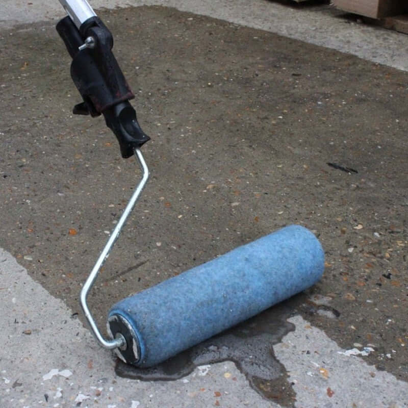 An image of SikaBond SBR Waterproofer & Bonding Admixture being applied to concrete with a roller.