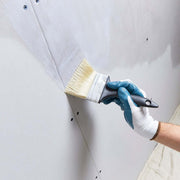 An image of SikaBond SBR Waterproofer & Bonding Admixture being applied to a plasterboard wall with a brush.