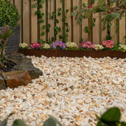 An image showing Spanish Gold Marble Stone Aggregate Chippings when laid has part of a garden.