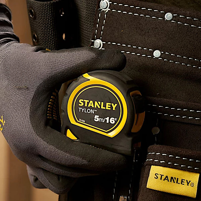 An image of a Stanley Tylon Tape Measure that is clipped to a work mans belt pouch