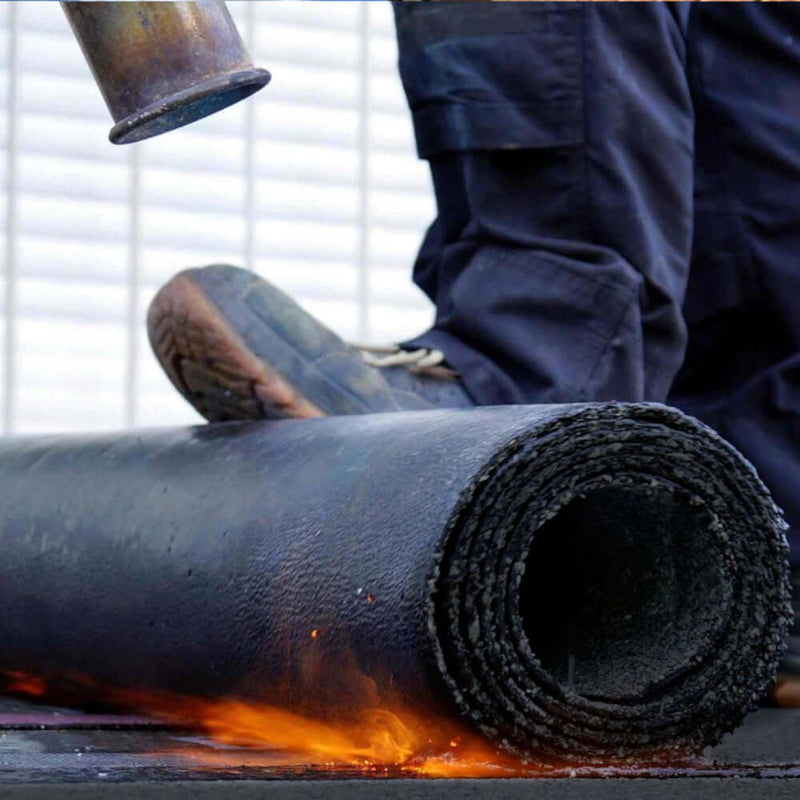 An image of a roll of torch on felt being heated with a flame and rolled onto a roof.
