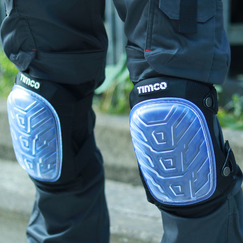 An image of Timco Knee Pads that come in one size. The image shows what they look like fastened onto legs. They are black and have a clear PVC non-slip gel filled pad.