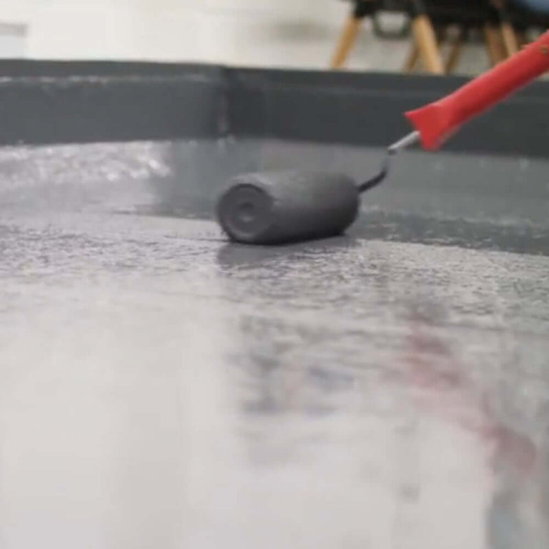 An image of Ultraflex Liquid Roofing being applied onto a roof with a roller.