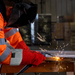 A pair of Red Welders Gauntlets / Gloves that have a grey cuff being used to weld metal.