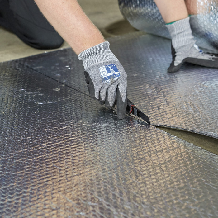 An image of YBS Airtec bubble aluminium foil insulation being cut with a Stanley knife so show it can be cut to size.