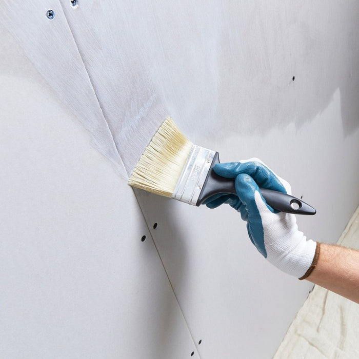 An image of Feb Febond SBR Waterproofer & Bonding Admixture being applied to a plasterboard wall with a brush.