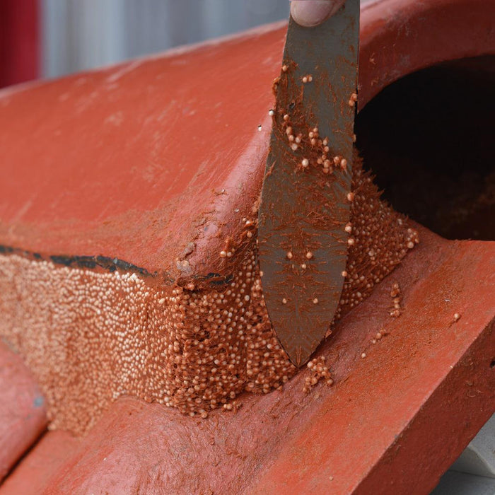 A Flexim Rooff putty knife being used to smooth of some Roof Putty that has been applied to ridge tiles on the apex of a roof.